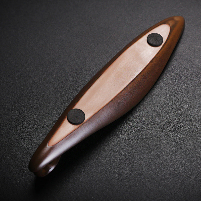The Drift incense burner — leaf-shaped dark wood single-stick holder with incense burning gently against a dark background.