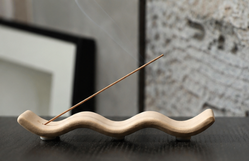 The Ripple minimalist Chinese incense holder on a wood table — sand-toned ceramic, hill silhouette, holds standard sticks