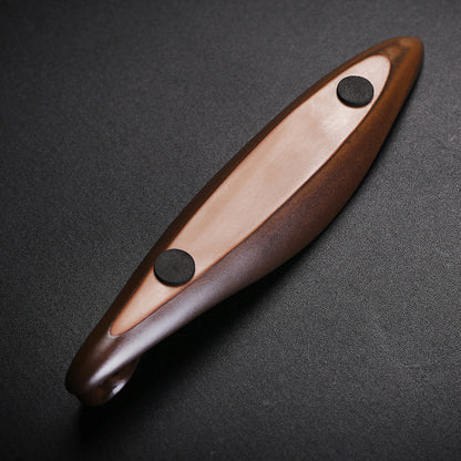 The Drift incense burner — leaf-shaped dark wood single-stick holder with incense burning gently against a dark background.